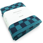 Folded teal and navy checkered kitchen towel with a white label on a white background